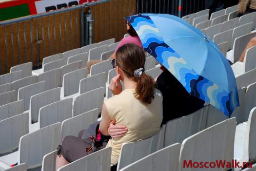зрители спасаются от палящего солнца зонтиками
