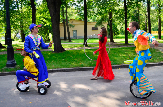 Клоуны на детском велосипеде жанглируют с артистом на моноцикле