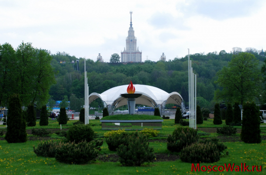 памятник олимпийскому огню на фоне МГУ